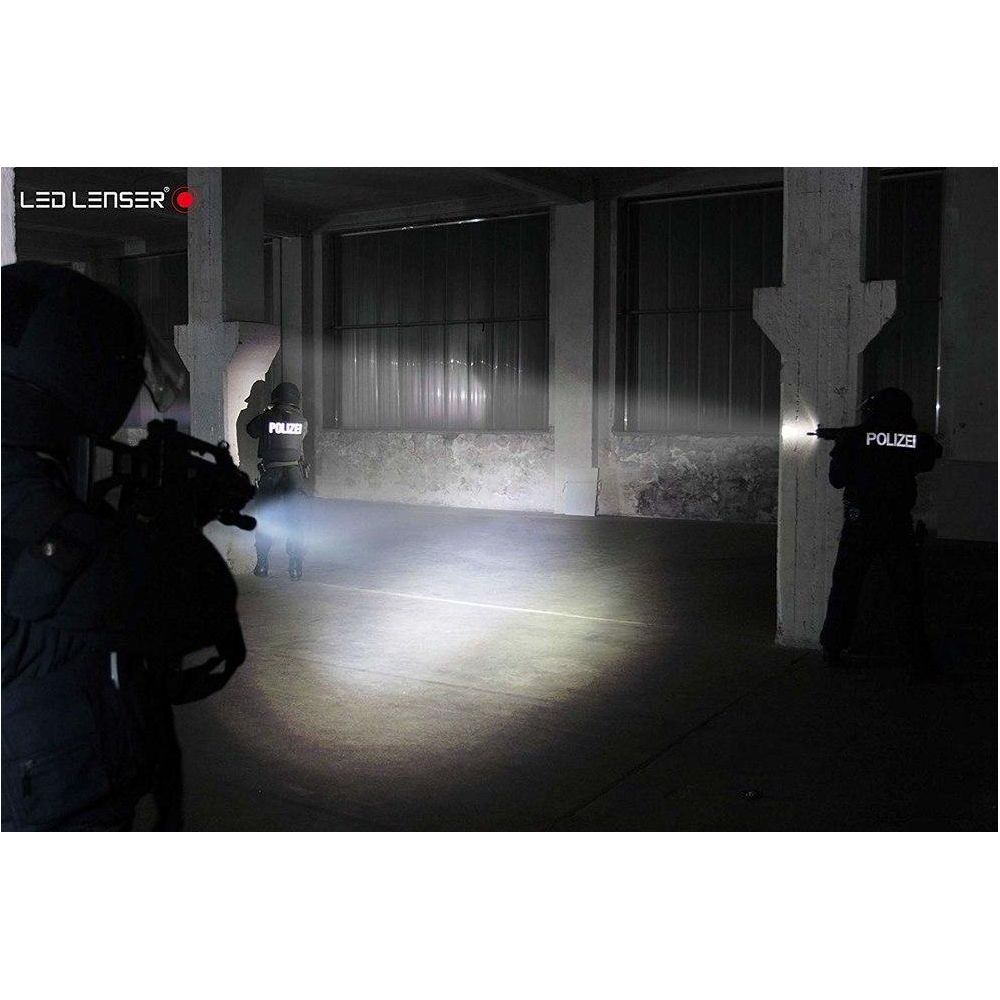 Policjanci w ciemnej hali oświetlają teren latarkami.