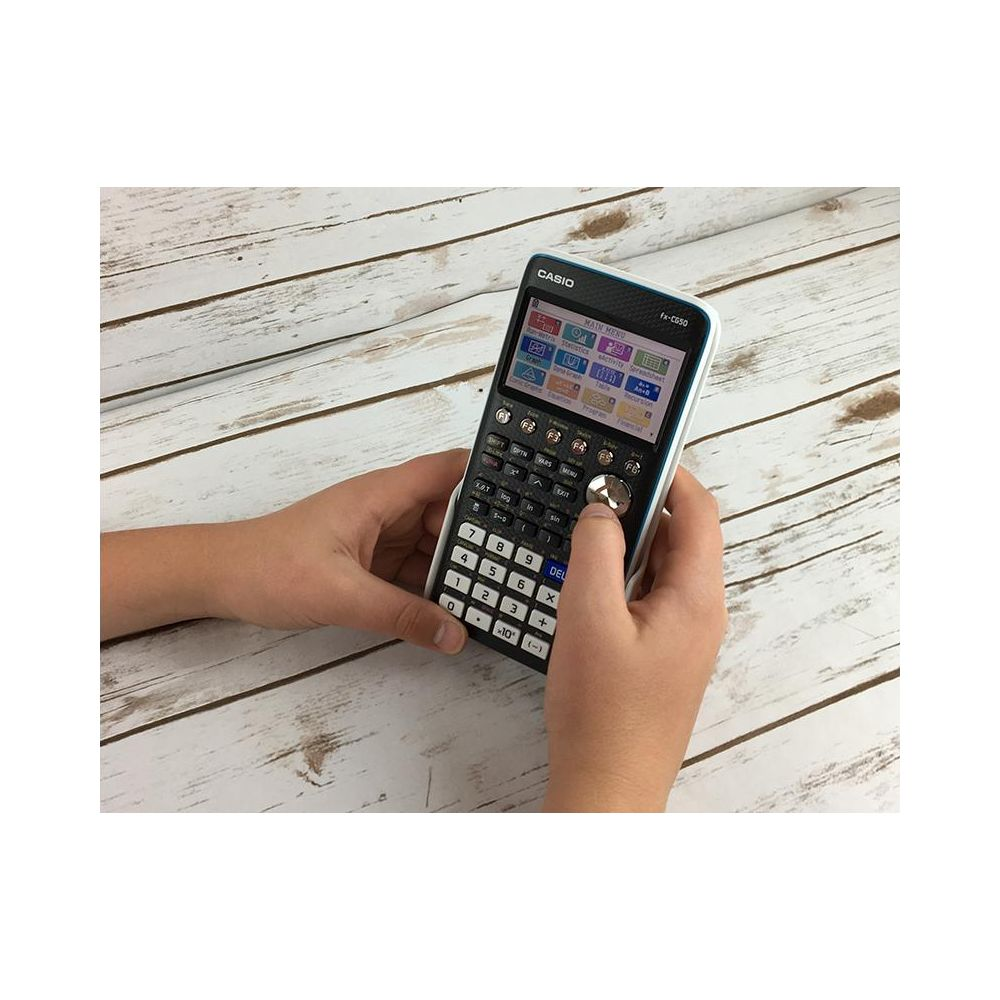 Dłonie trzymają kalkulator Casio z kolorowym menu na drewnianym tle.