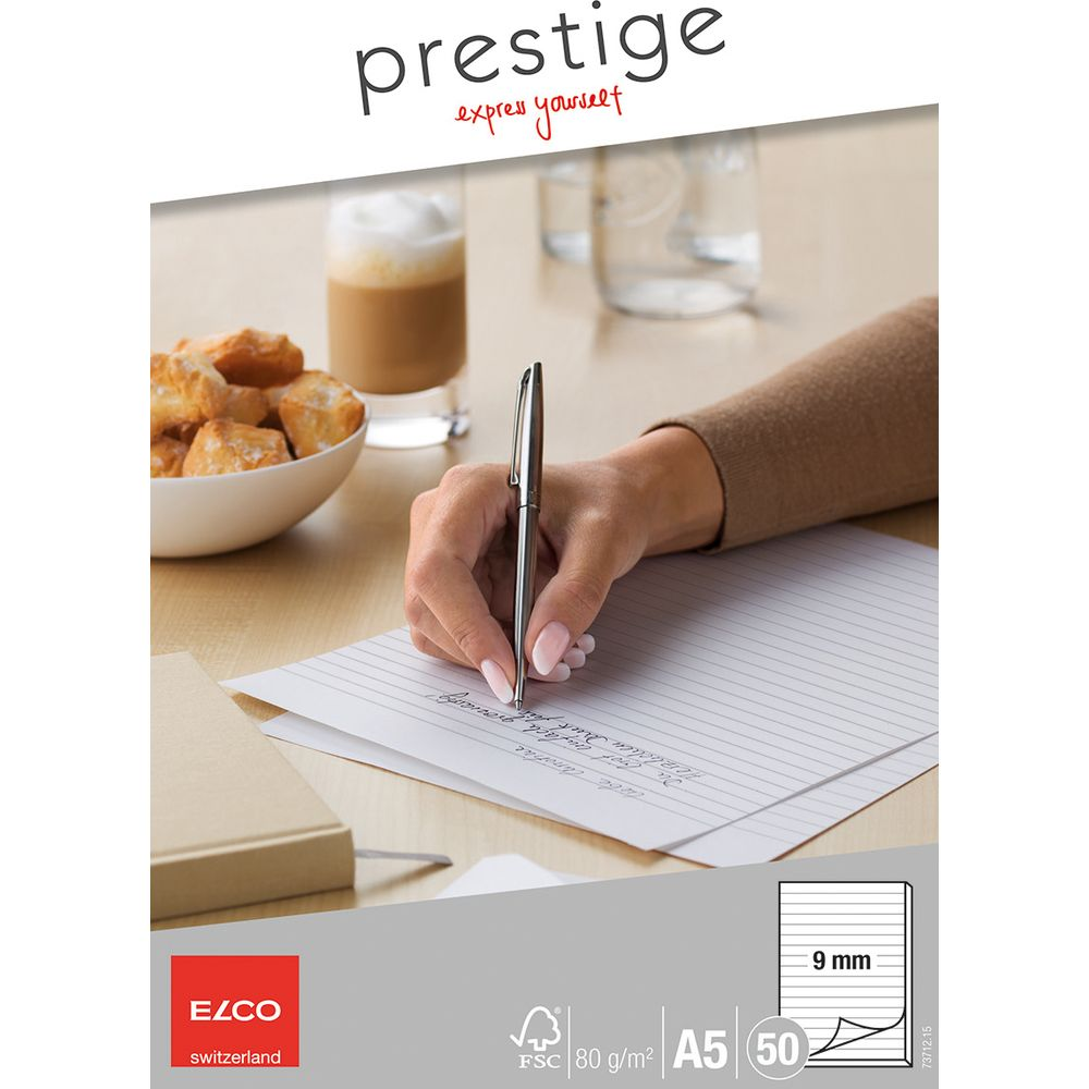 Eine Hand schreibt auf liniertem Papier, daneben ein Kaffee und Gebäck.