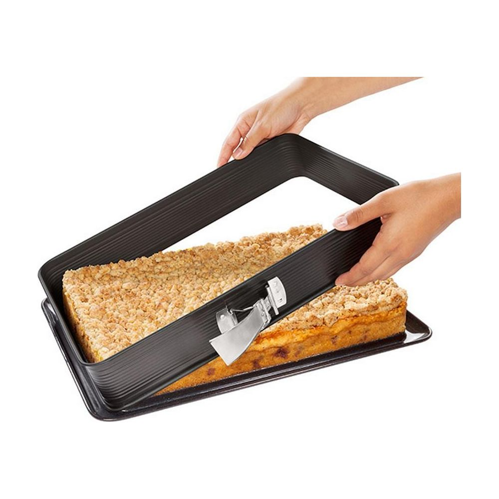 Ein rechteckiger Kuchen mit Krümelbelag wird aus einer Form gehoben.