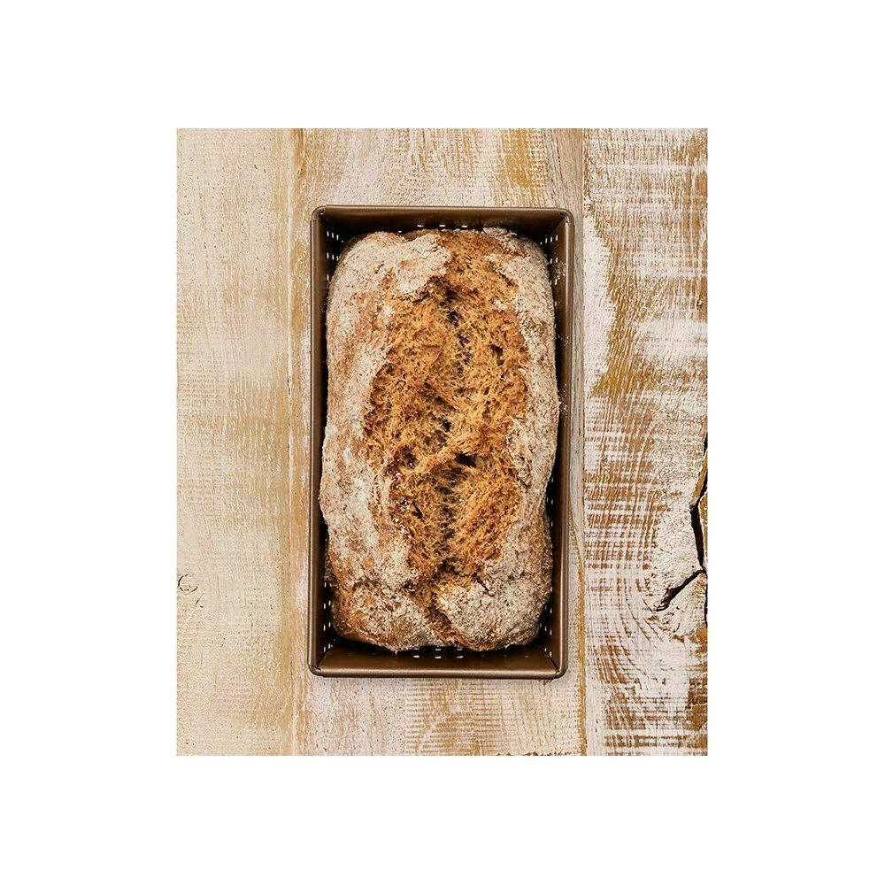 Ein Laib dunkles Brot mit knuspriger Kruste in einer rechteckigen Backform auf Holztisch.