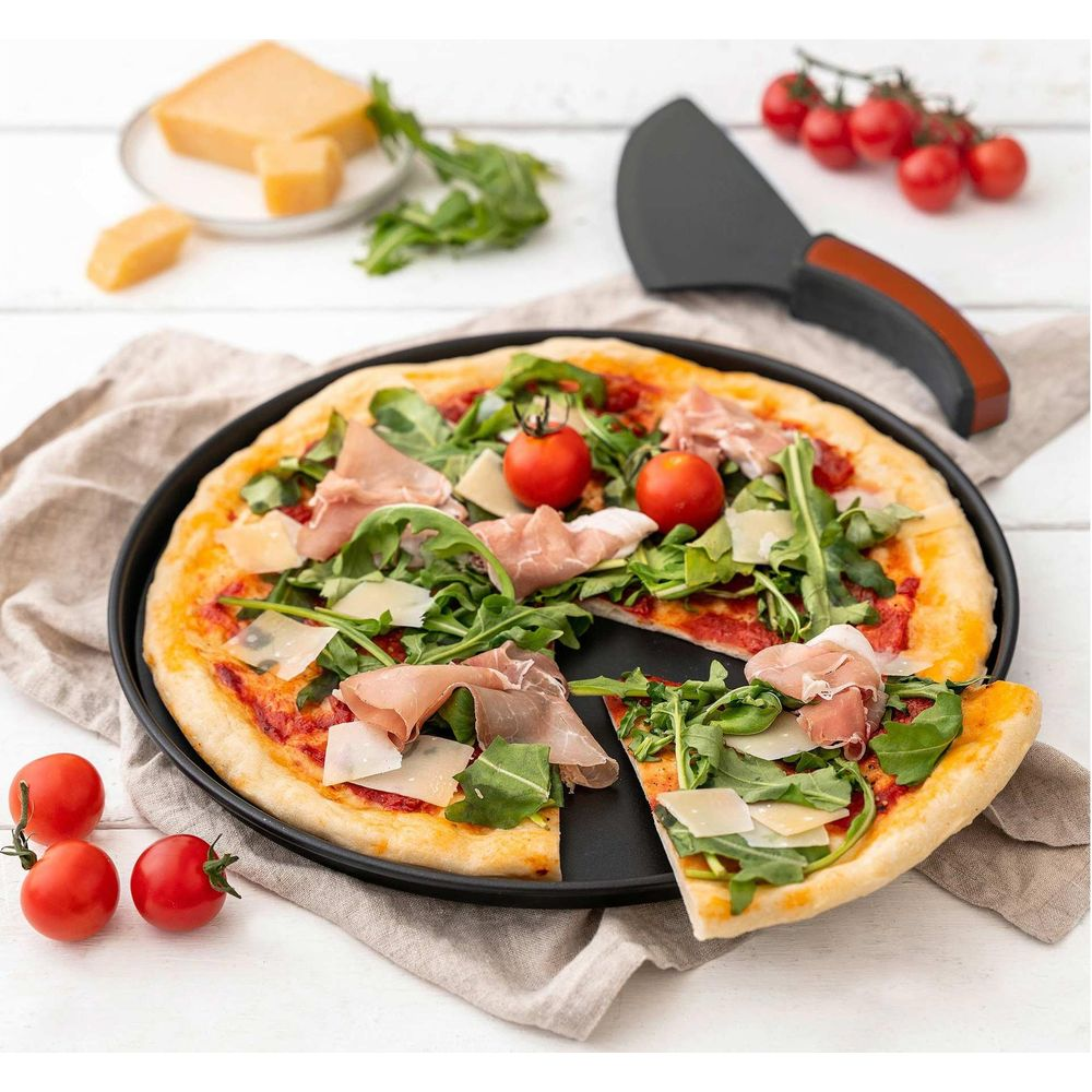 Eine Pizza mit Prosciutto, Rucola und Kirschtomaten auf einem Teller, daneben Käsewürfel.