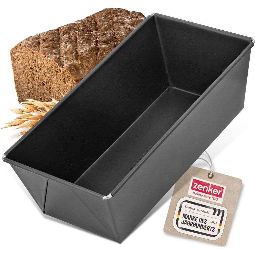 Ein rechteckiger Backkasten aus dunklem Metall mit einem Laib Brot und Weizenähren daneben.