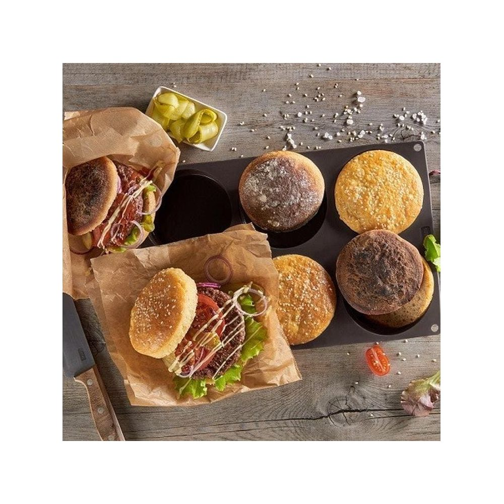 Dwa burgery z bułkami, ogórkami i kotletami na drewnianym stole.