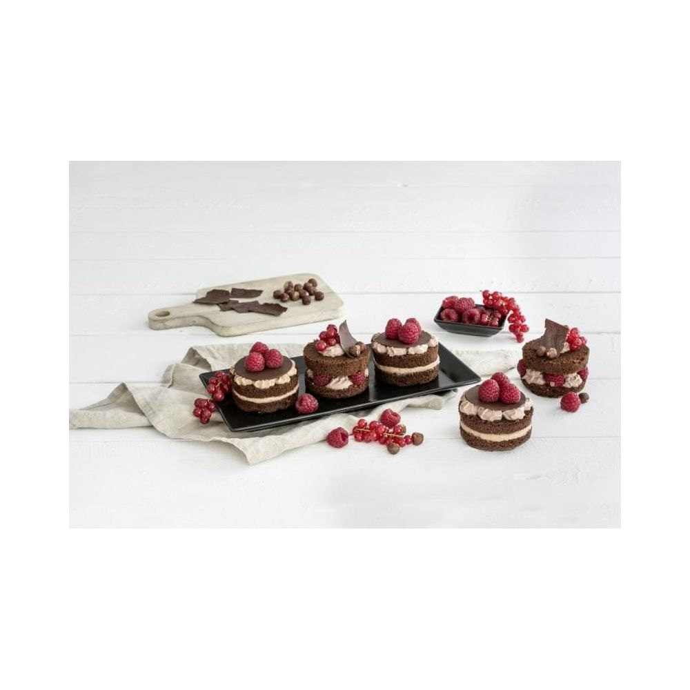 Schokoladenkuchen mit Beeren und Sahne auf schwarzer Platte.