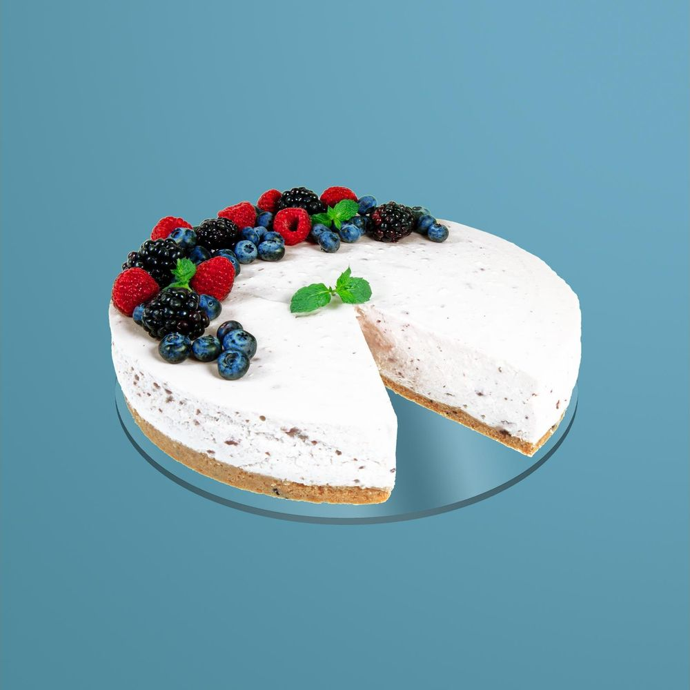 Ein weißer Kuchen mit Beeren und Minze auf blauem Hintergrund.