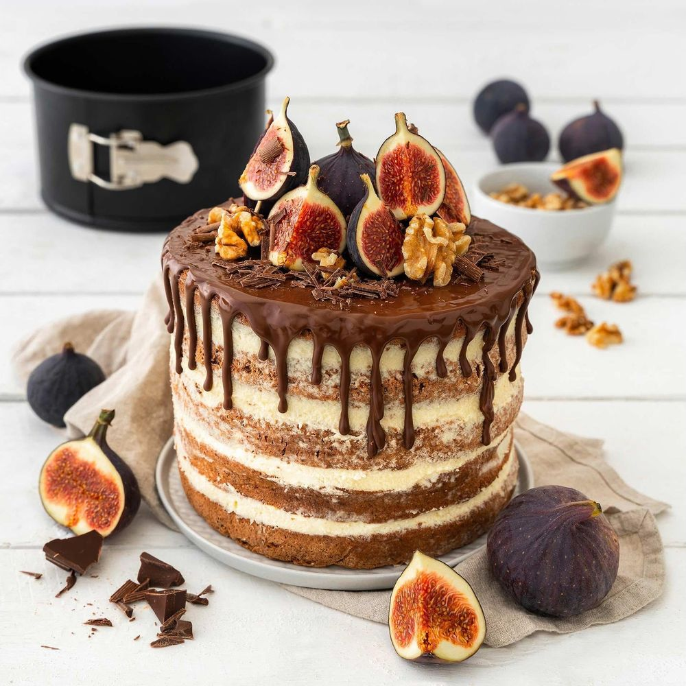 Ein Schokoladen-Drip-Kuchen mit Feigen und Walnüssen, garniert mit Schokoladenraspeln.
