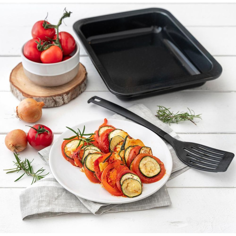 Ein Ratatouille-Gericht mit Tomaten und Zucchini, neben Zutaten und einer Auflaufform.