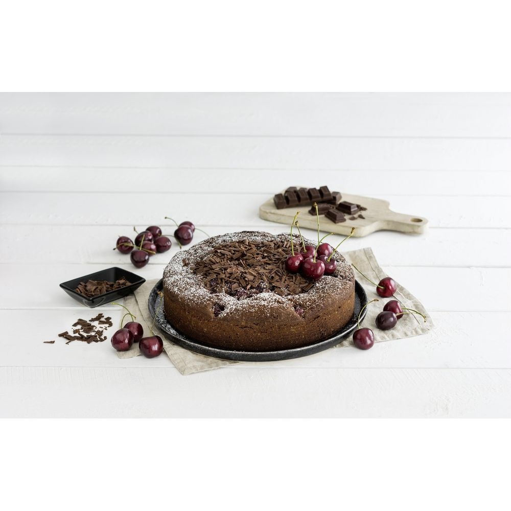 Schokoladenkuchen mit Kirschen und Schokostückchen auf einem Holztisch.