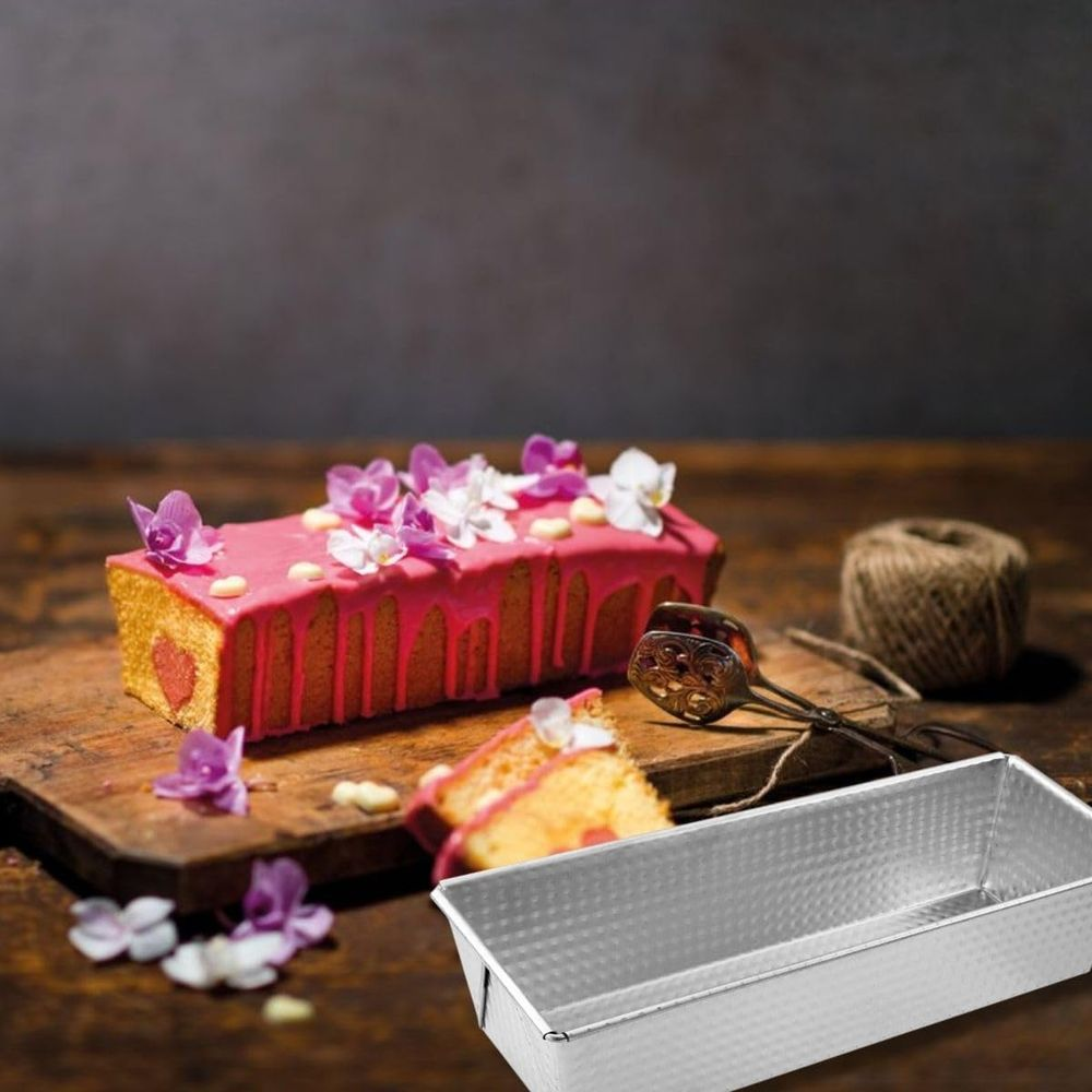 Ein rosa verzierter Kuchen mit Blumen, daneben eine Kuchenform.