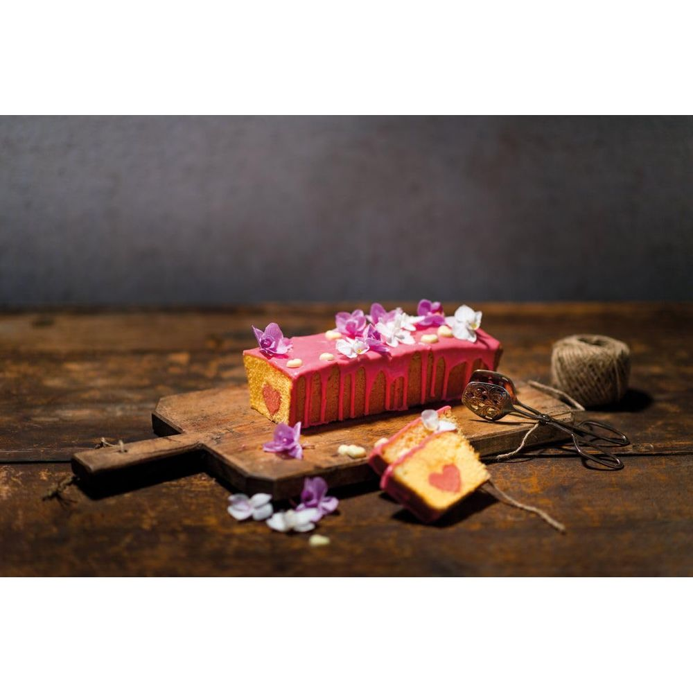 Ein rechteckiger Kuchen mit rosa Glasur und Herzmuster, verziert mit Blumen.