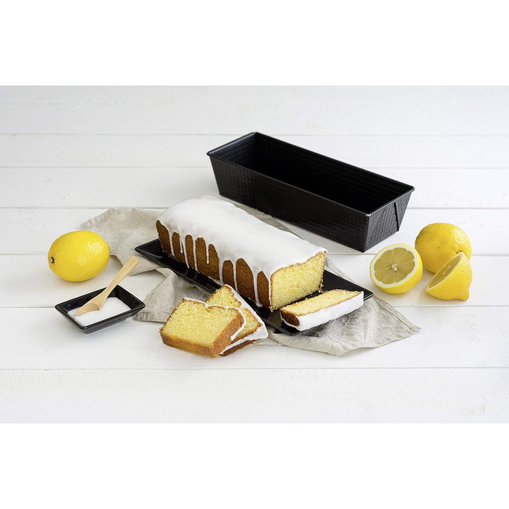 Ein Zitronenkuchen mit Zuckerguss, Scheiben, Zitronen und einer Backform.