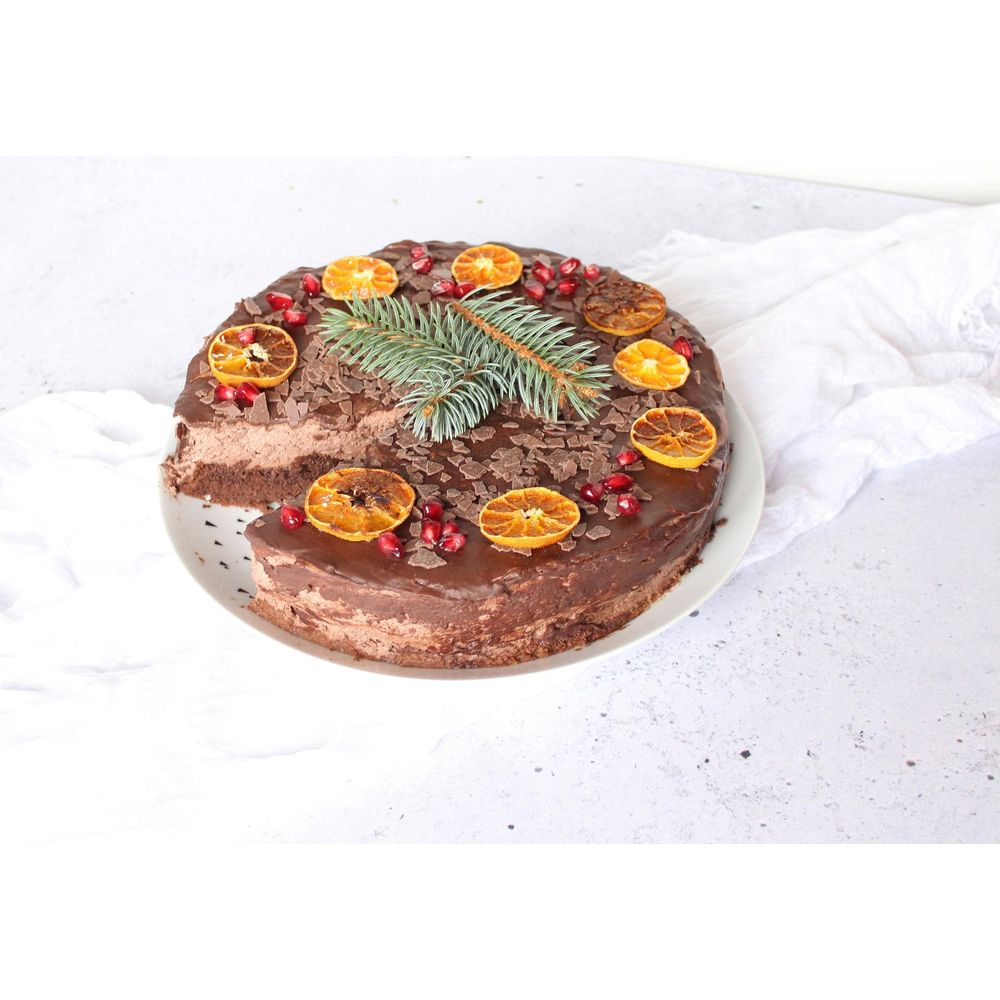 Schokoladenkuchen mit Glasur, Orangen, Granatapfelkernen und Tannenzweigen.