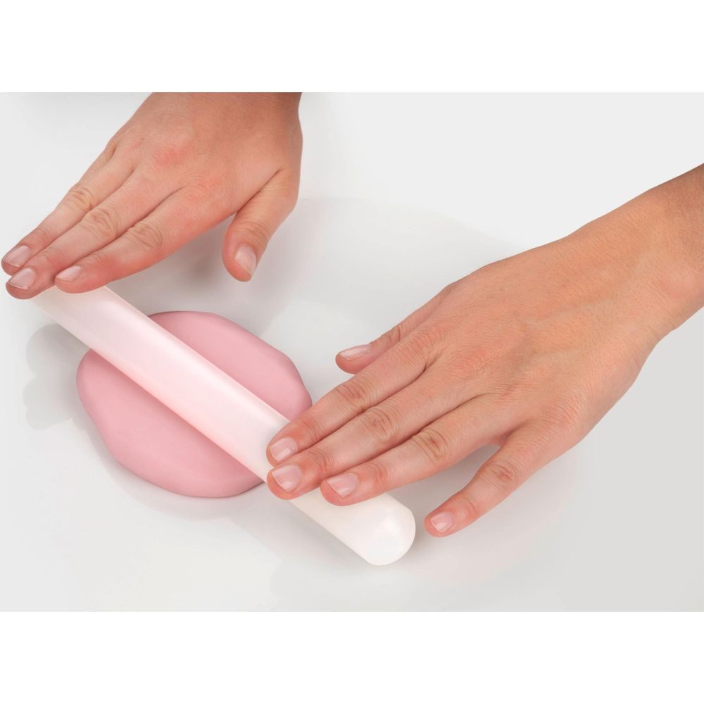 Hände rollen rosa Zuckermasse mit einem weißen Nudelholz auf einer weißen Fläche aus.