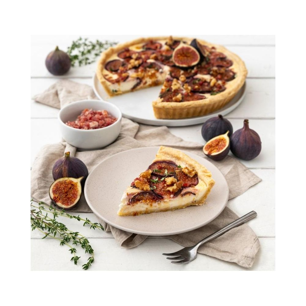 Ein Stück Feigenkuchen mit Walnüssen und Käse auf einem Teller, dahinter ein ganzer Kuchen.