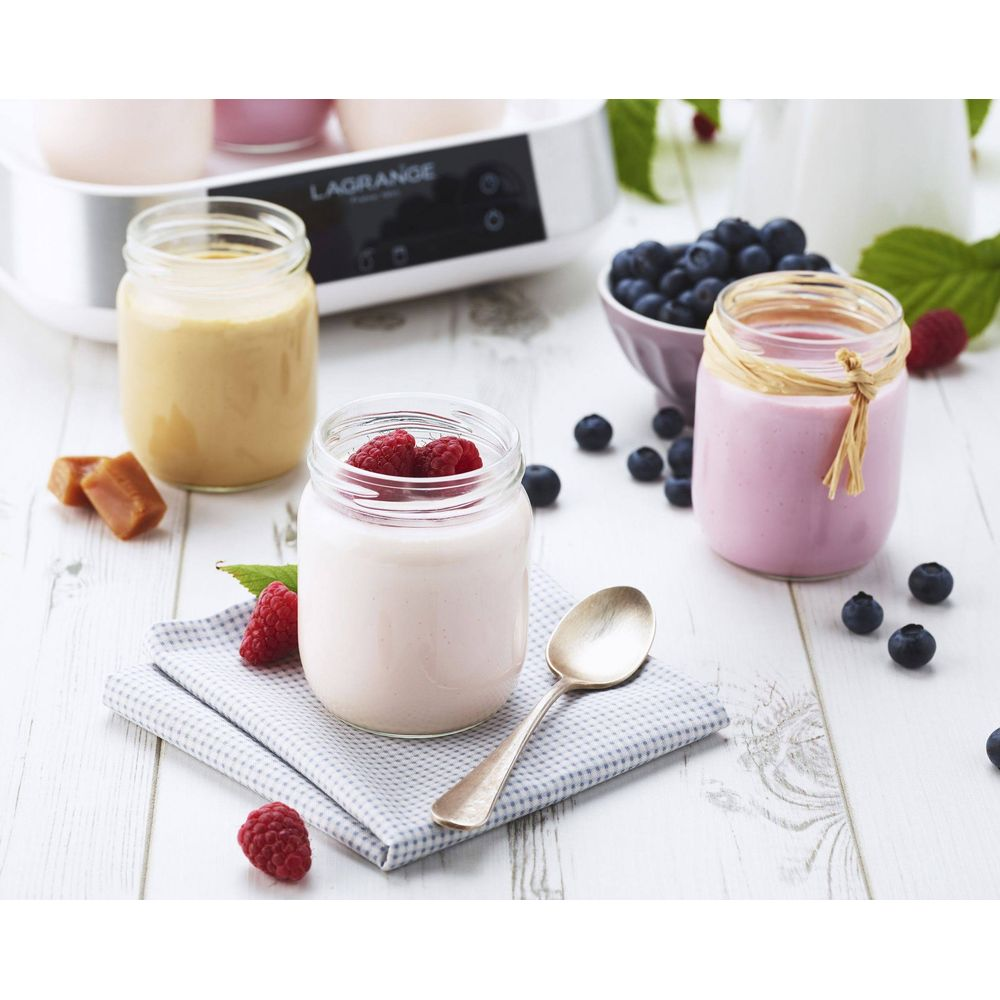 Drei Gläser Joghurt mit Beeren und Karamell, daneben ein Joghurtbereiter.