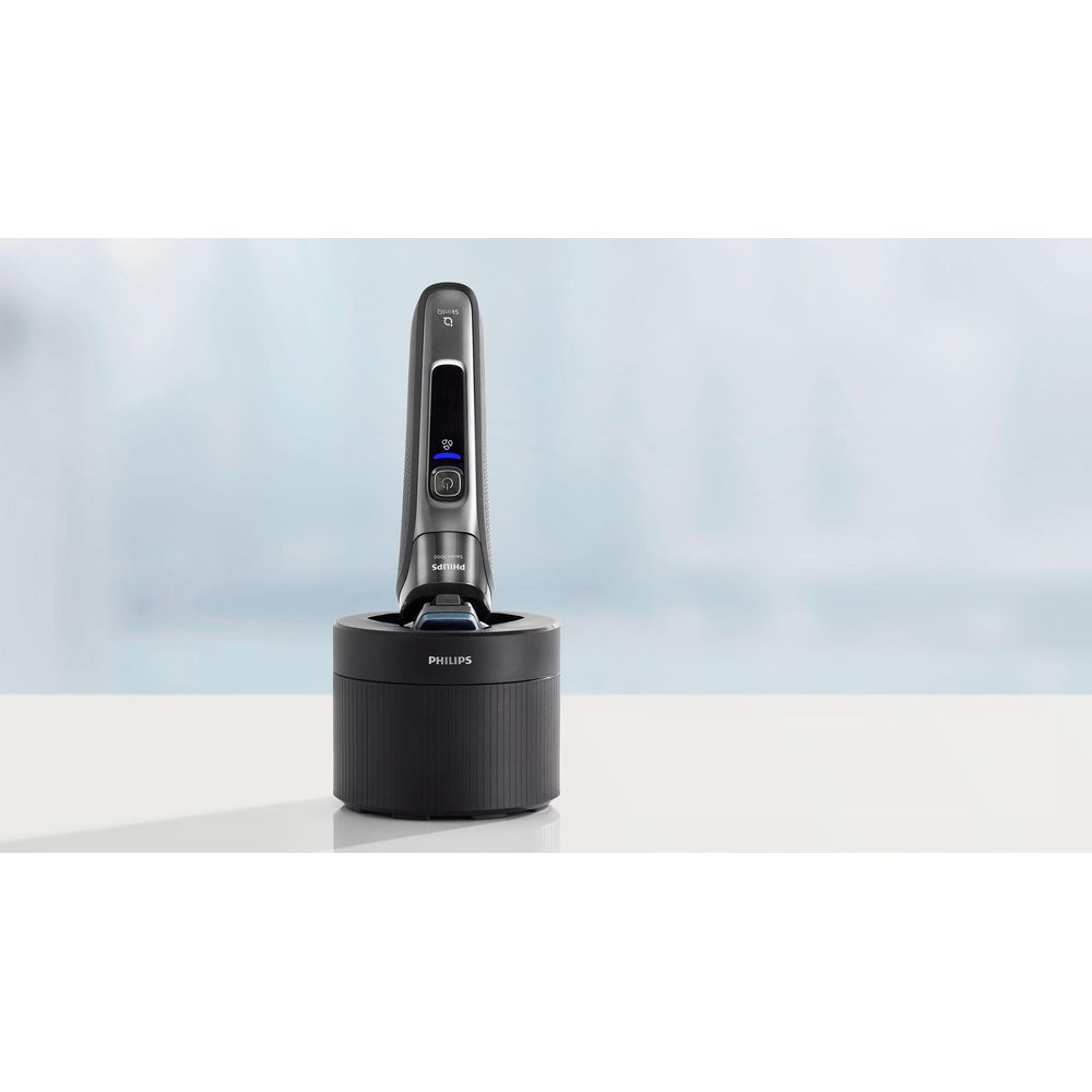 Una afeitadora Philips gris está sobre una base de carga.