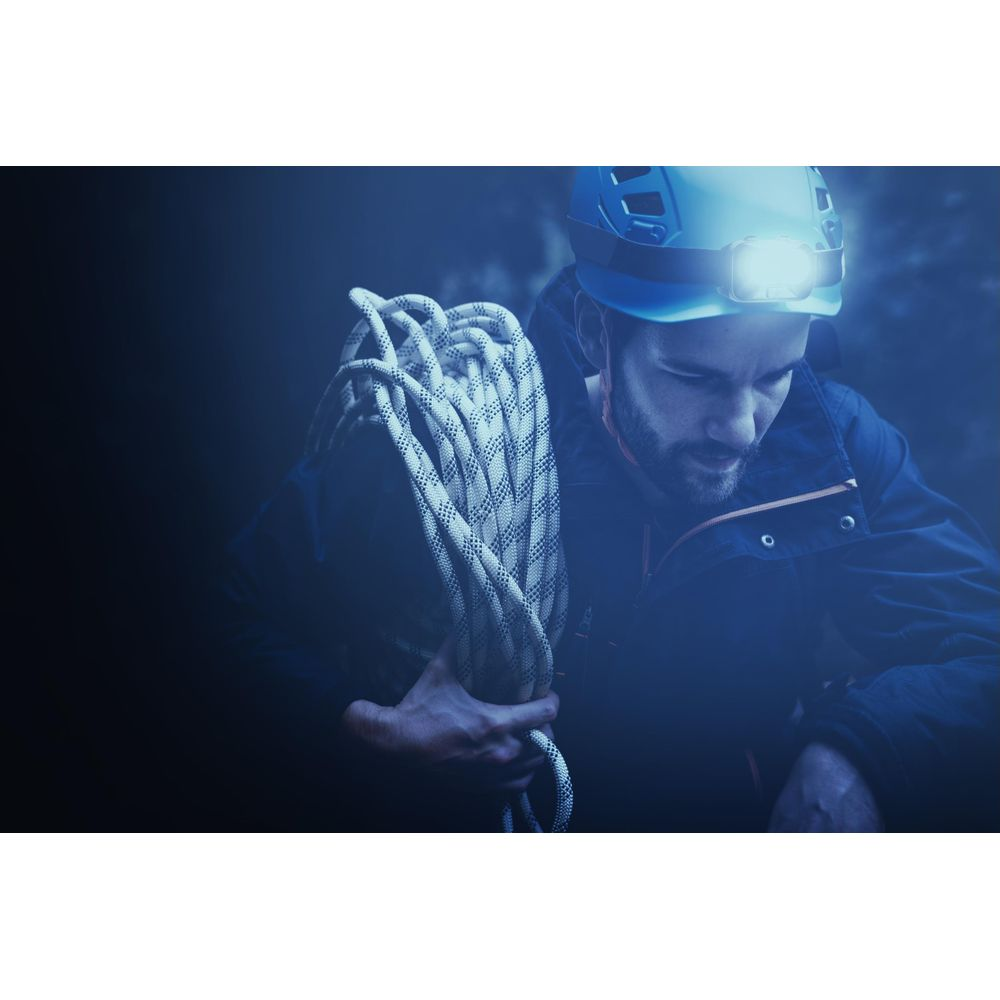 Ein Mann mit Helm und Stirnlampe trägt ein Seil.