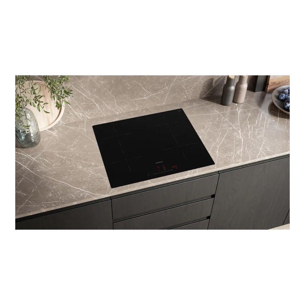 Une plaque à induction noire sur un plan de travail en marbre avec des meubles de cuisine.