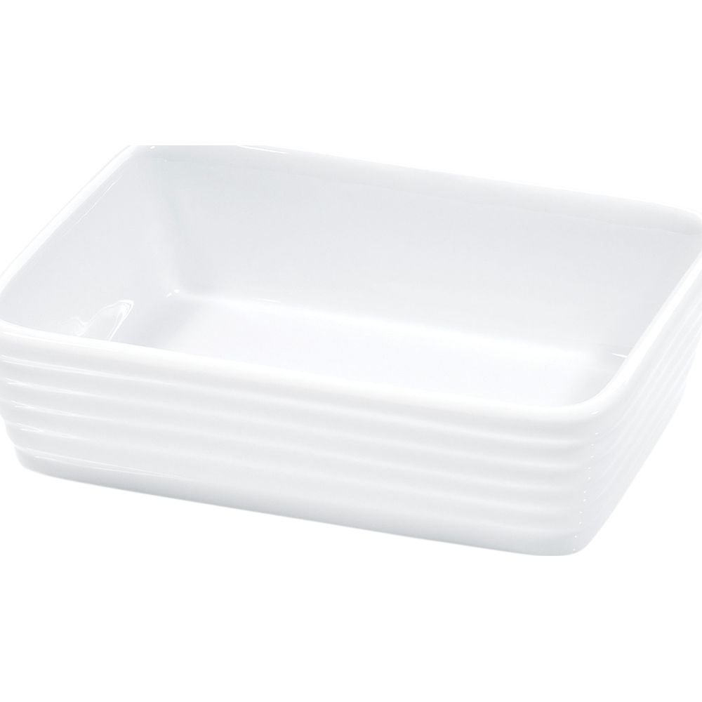 Un plat à gratin en céramique blanche à bords nervurés sur fond blanc.