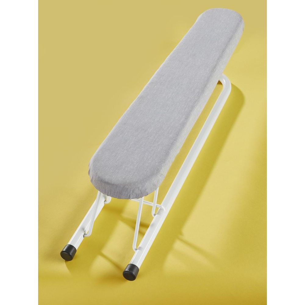 Un piccolo asse da stiro bianco con copertura grigia su sfondo giallo.