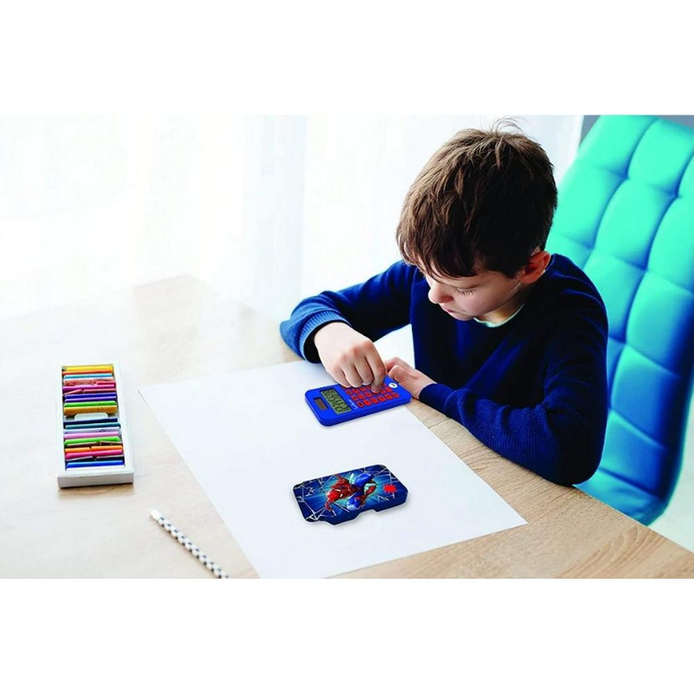 Ein Junge sitzt an einem Tisch und spielt mit einem blauen Taschenrechner und einem Spielzeug.