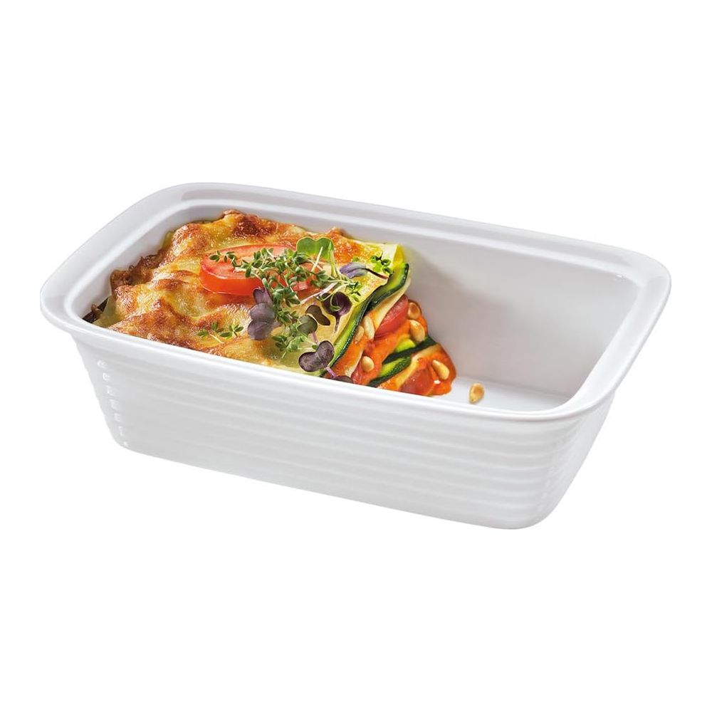 Lasagne in weißer Auflaufform, garniert mit Kräutern und Tomate.