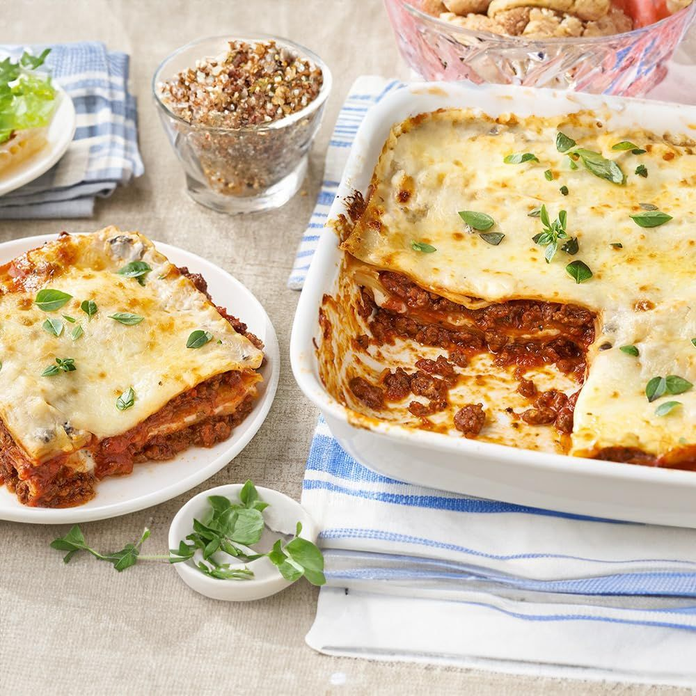 Lasagne in einer Auflaufform und auf einem Teller mit Käse überbacken.