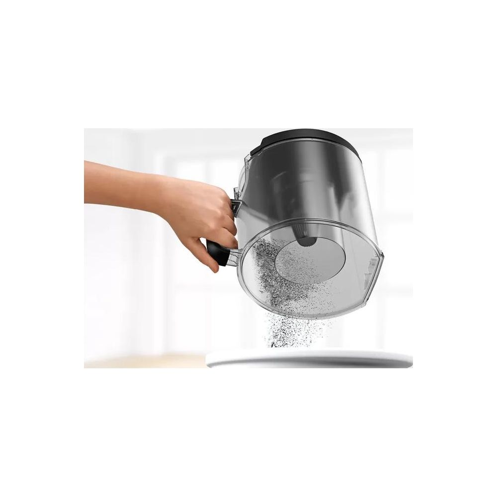 Ręka trzyma przezroczysty pojemnik na kurz, z którego wypada kurz.