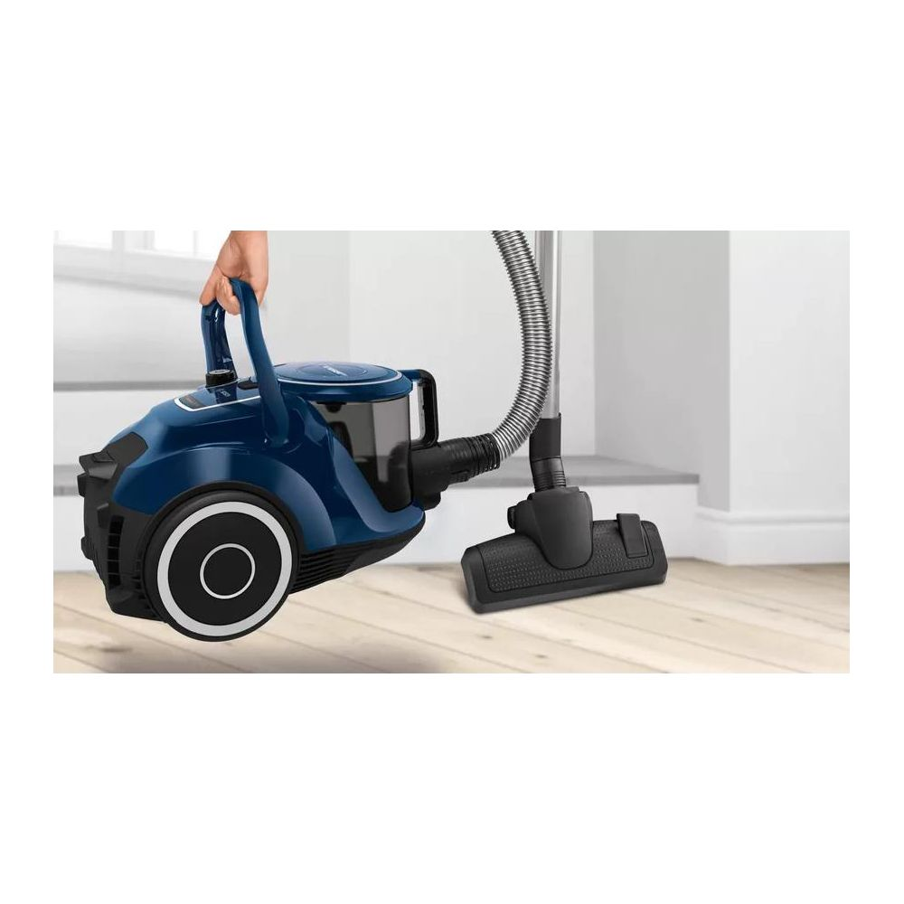 Niebieski odkurzacz z wężem i szczotką na drewnianej podłodze.