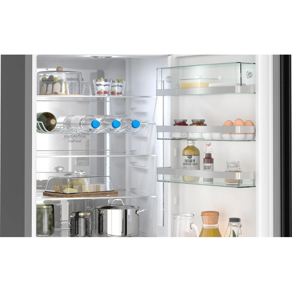Interior de refrigerador con botellas, huevos, queso, frascos y una olla.