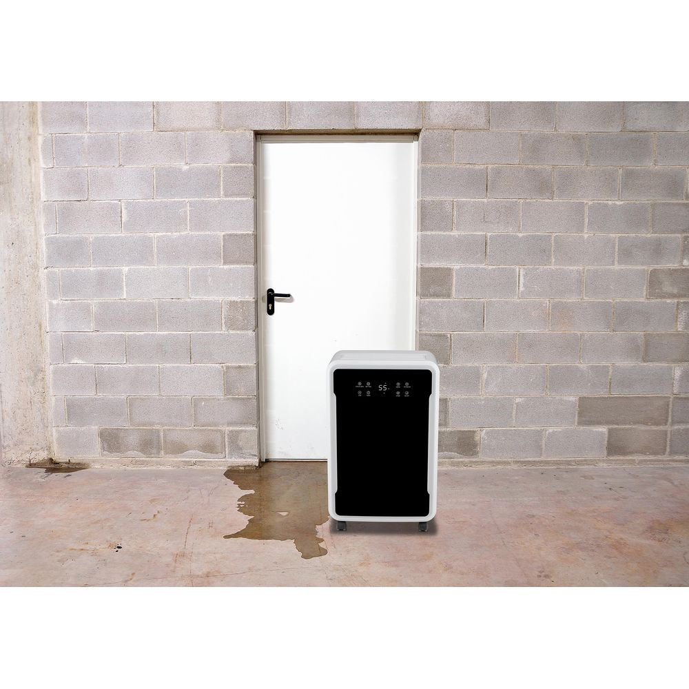 Un deumidificatore bianco con display nero si trova davanti a una porta bianca, con macchie d'acqua nelle vicinanze.
