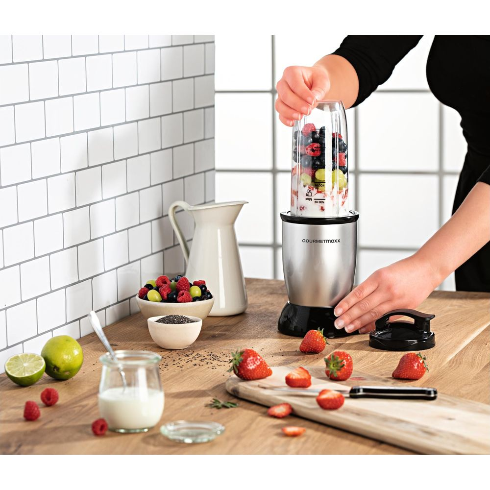 Eine Person bereitet einen Smoothie mit Beeren und Joghurt in einem Mixer zu.