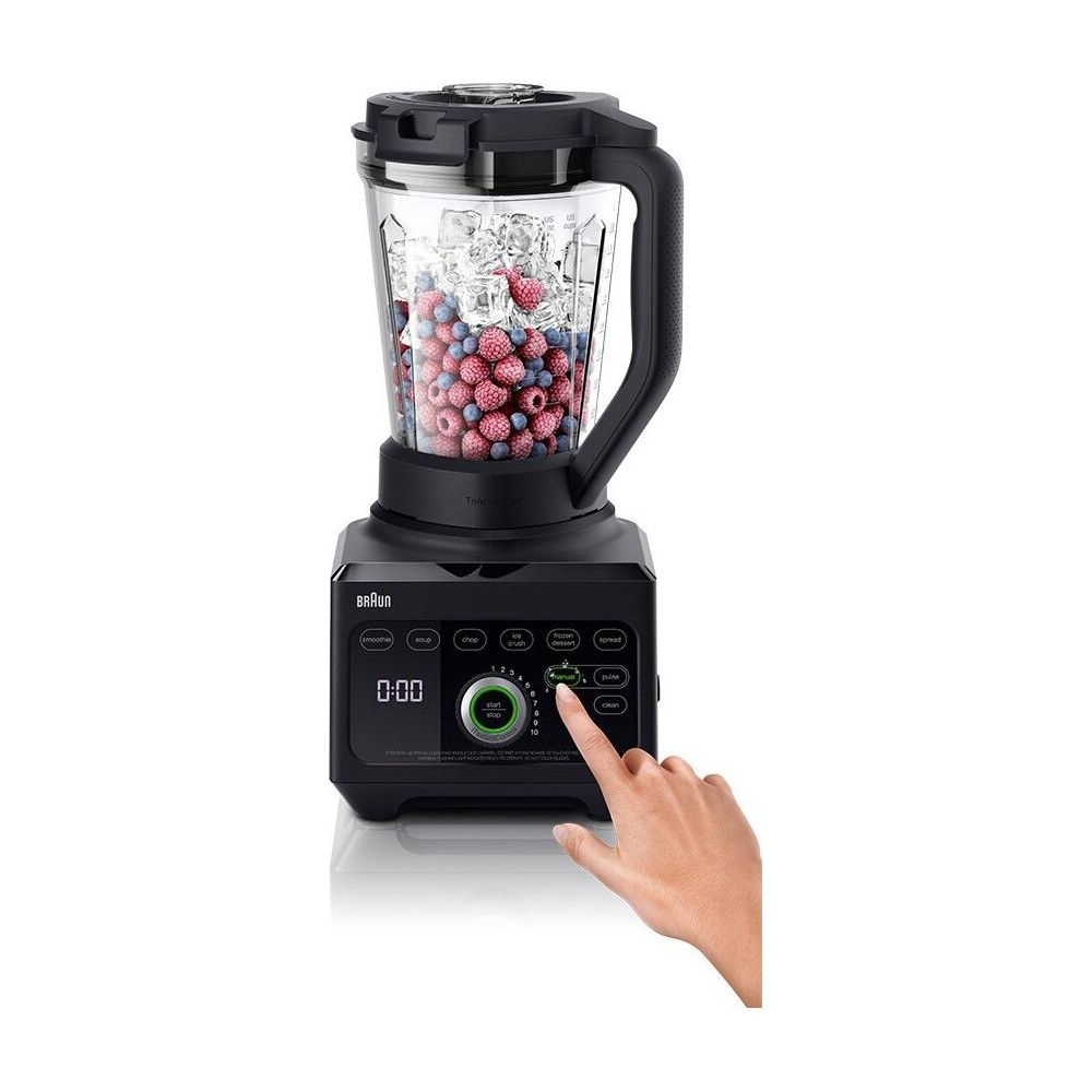 Un frullatore nero con bacche e ghiaccio, una mano preme un pulsante.