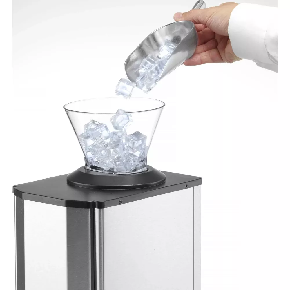 Una mano versa cubetti di ghiaccio da una paletta in un bicchiere sopra una macchina del ghiaccio.