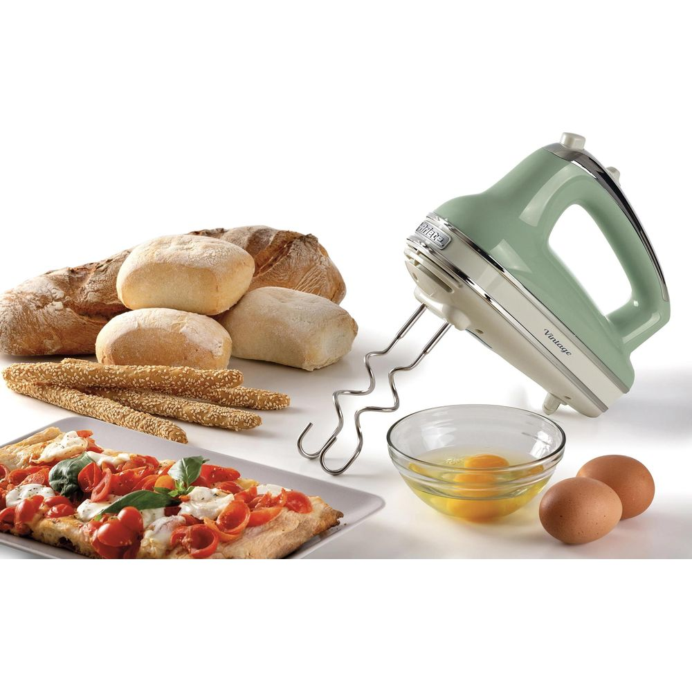 Ein grüner Handmixer mit Backzutaten: Brot, Brötchen, Pizza, Eier und eine Schüssel mit Eiern.