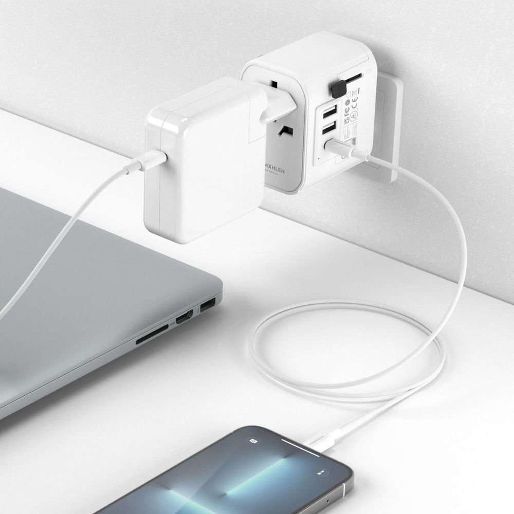 Een witte universele adapter laadt een laptop en smartphone op.
