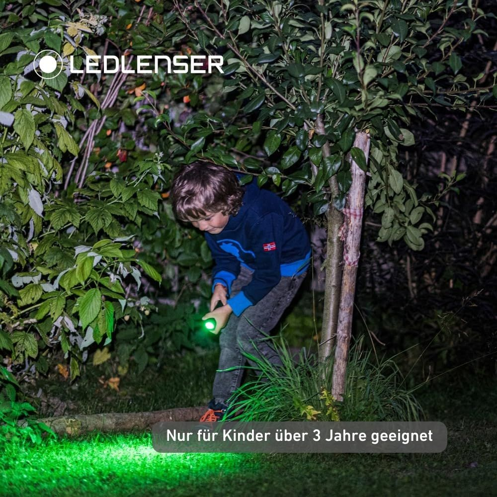 Un ragazzo illumina un cespuglio con una torcia verde.