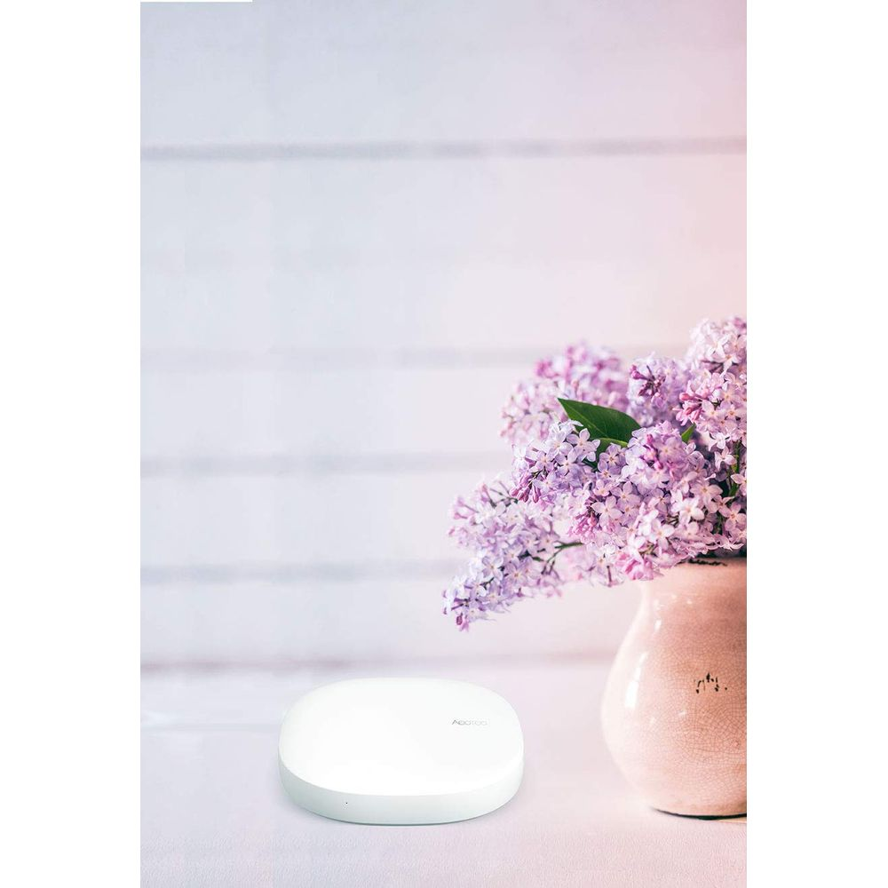 Białe urządzenie i bukiet bzu w wazonie na stole.