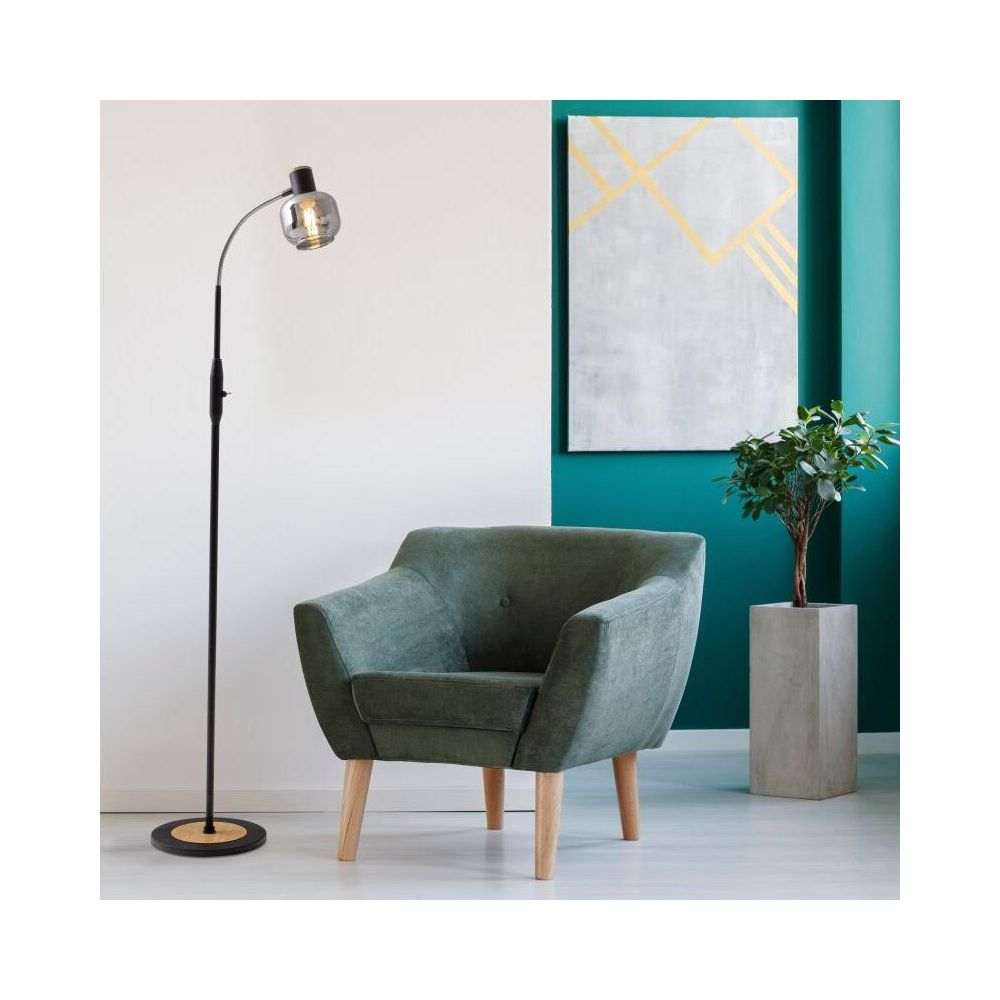 Ein grüner Sessel steht neben einer Stehlampe und einem Gemälde.