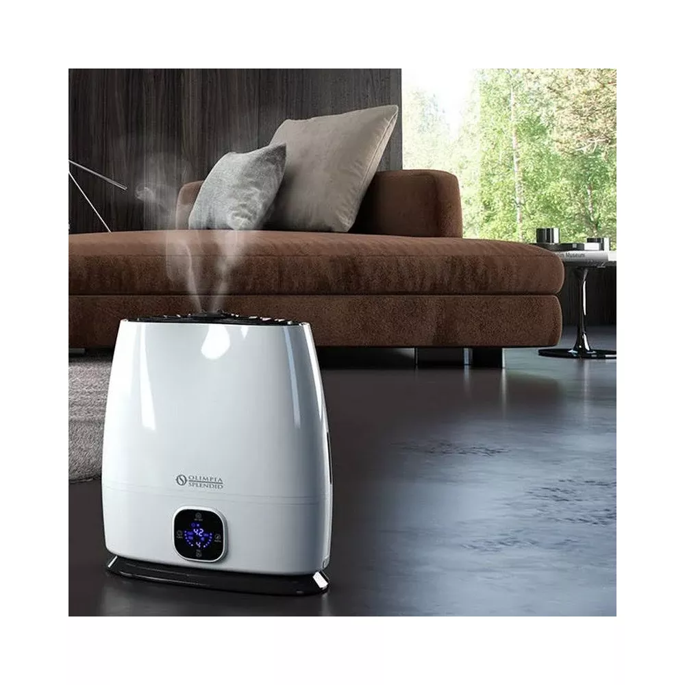 Un humidificador blanco emite vapor, junto a un sofá marrón.