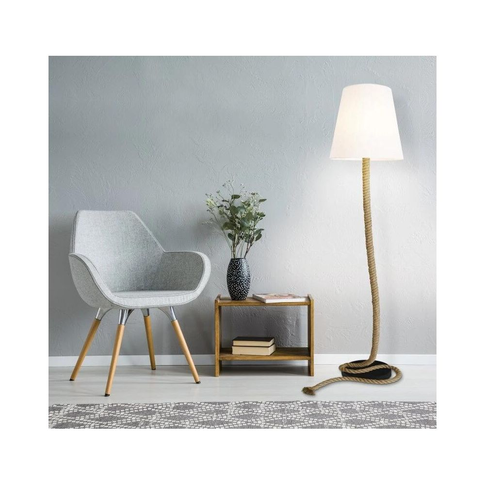 Ein grauer Sessel steht neben einem Holztisch mit Vase und Büchern. Eine Stehlampe steht rechts.