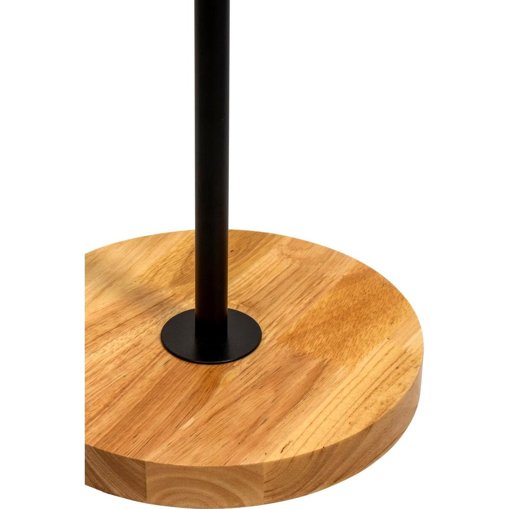 Czarny metalowy słup stoi na okrągłej drewnianej podstawie.