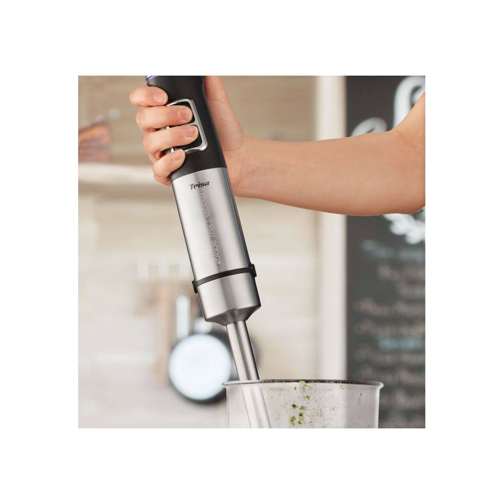 Eine Hand hält einen silbernen Stabmixer über einem Glas mit grüner Flüssigkeit.