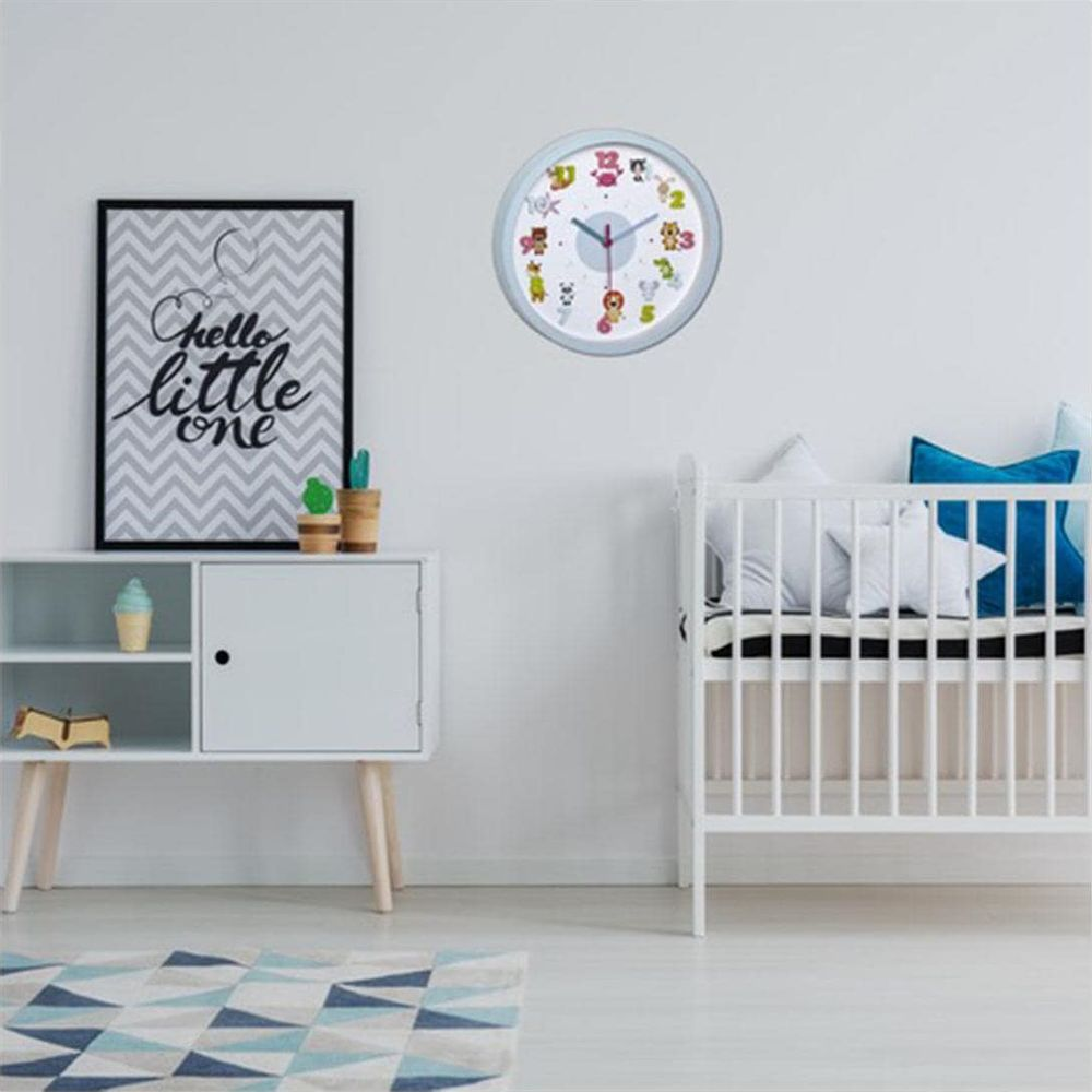 Ein Kinderzimmer mit einem Kinderbett, einem weißen Schrank, einem gerahmten Bild und einer Wanduhr.