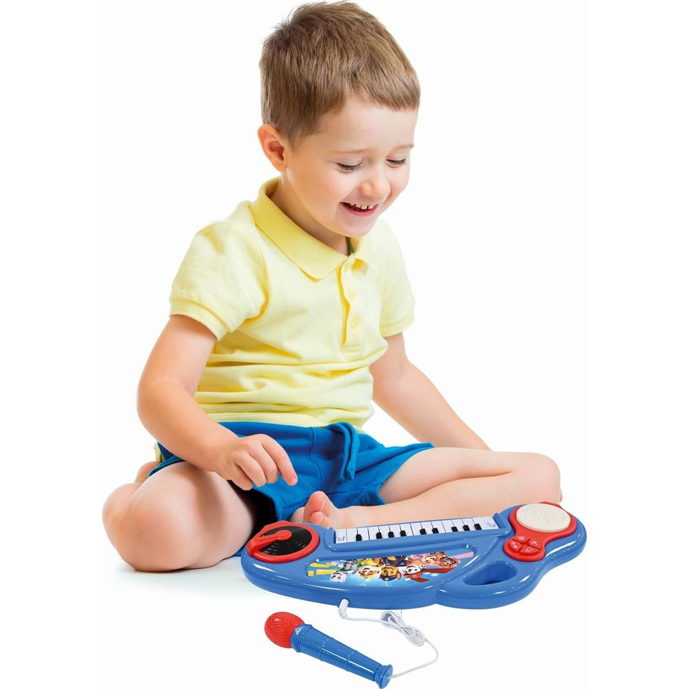 Chłopiec gra na niebieskich zabawkach pianino z mikrofonem.