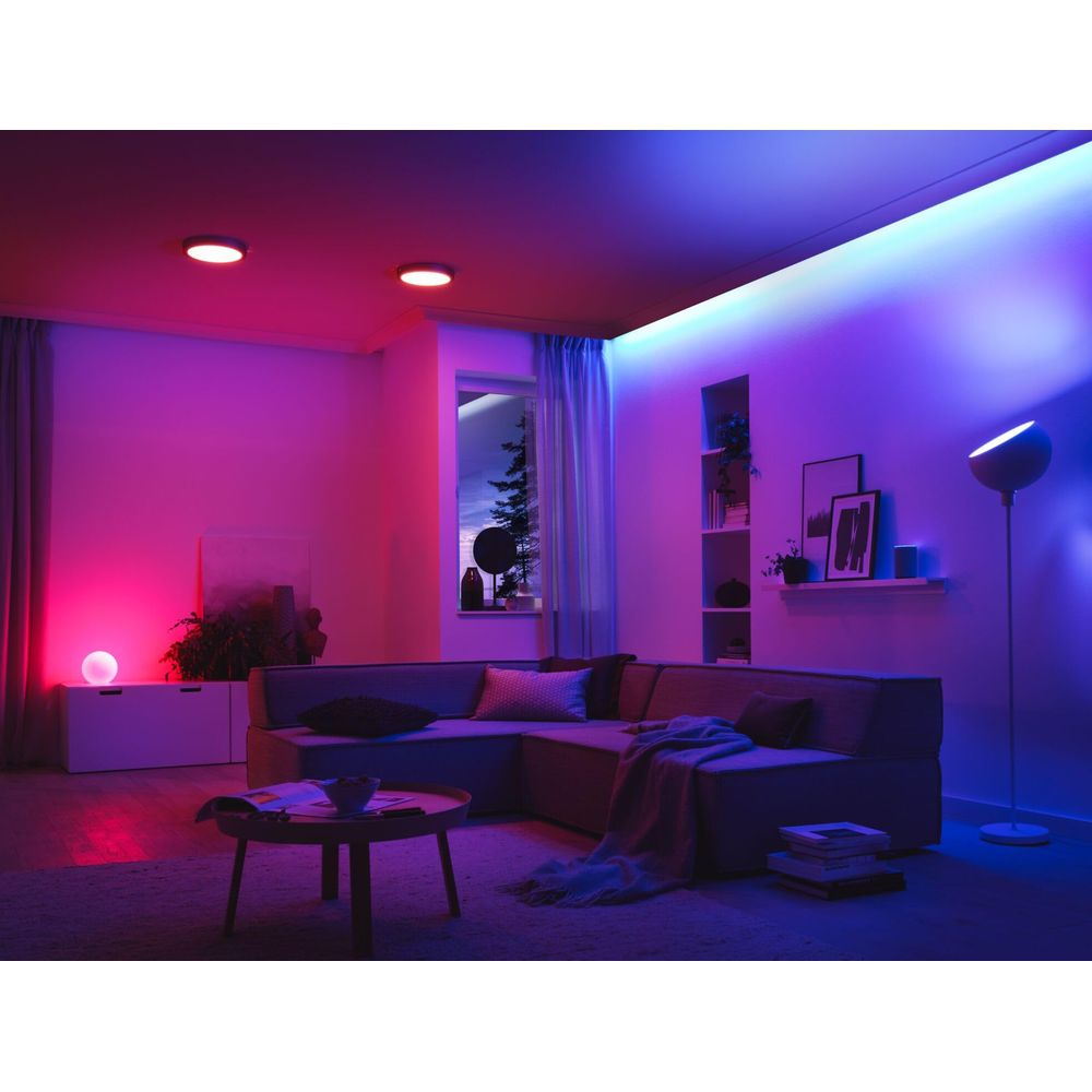 Ein Wohnzimmer mit einem Ecksofa, beleuchtet von rotem und blauem Licht.