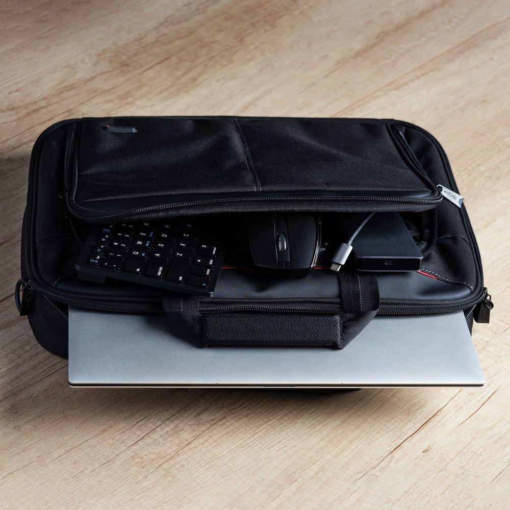 Un laptop nero spunta da una borsa, con tastiera, mouse e cavi all'interno.