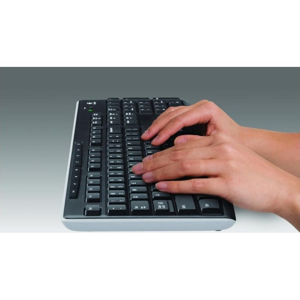 Hände tippen auf einer schwarzen Tastatur mit silbernem Rahmen.