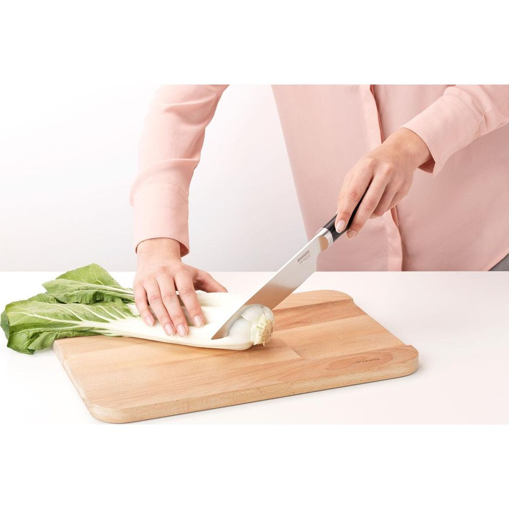 Person schneidet Chinakohl auf einem Holzbrett mit einem Messer.